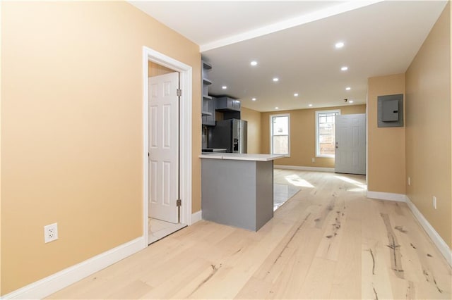 kitchen with a peninsula, fridge with ice dispenser, recessed lighting, and light wood-style floors