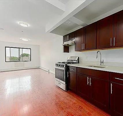 kitchen with sink, gas range, and hardwood / wood-style flooring