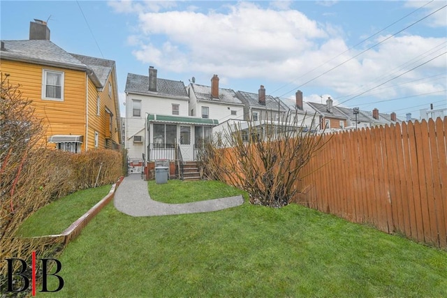 back of property with a lawn, fence, and a sunroom