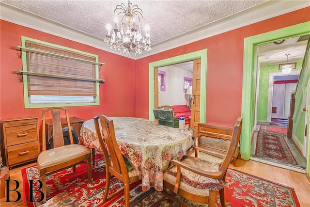 dining space featuring a textured ceiling, an inviting chandelier, and wood finished floors