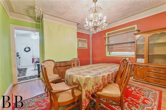 dining area with a textured ceiling, an AC wall unit, wood finished floors, and ornamental molding