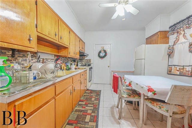 kitchen with tasteful backsplash, under cabinet range hood, light countertops, range with gas stovetop, and light tile patterned flooring