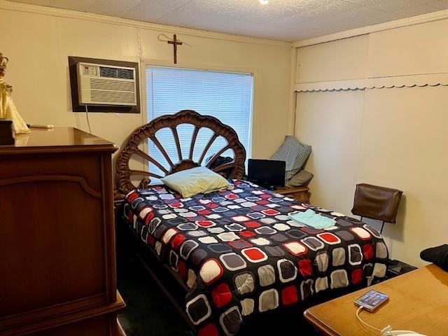 bedroom with a textured ceiling, ornamental molding, and a wall mounted AC