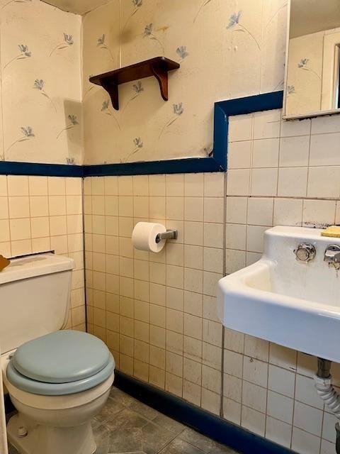 bathroom featuring sink, toilet, tile patterned flooring, and tile walls