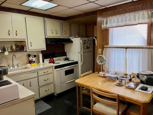 kitchen with a paneled ceiling, sink, backsplash, white cabinets, and white appliances