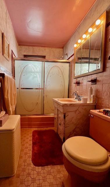 bathroom with tile walls, vanity, crown molding, and a shower