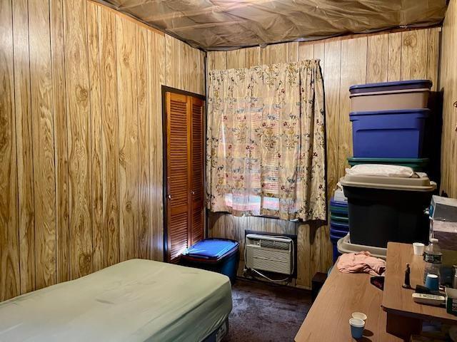 bedroom with a wall mounted AC and wood walls