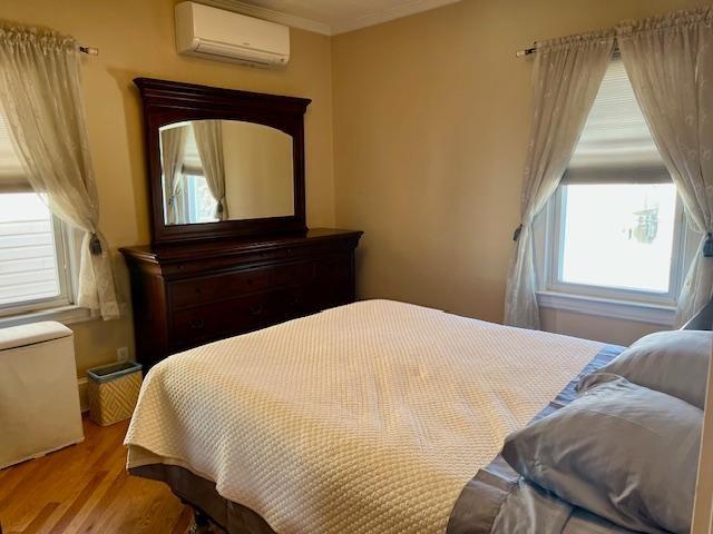 bedroom with a wall mounted air conditioner and light wood-type flooring