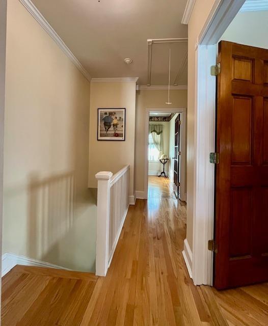 hallway with ornamental molding and light hardwood / wood-style floors