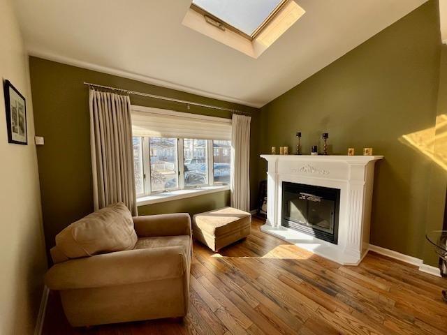 sitting room with wood-type flooring and lofted ceiling with skylight