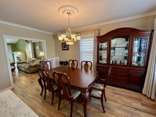 dining room featuring a notable chandelier, ornamental molding, and light wood-type flooring