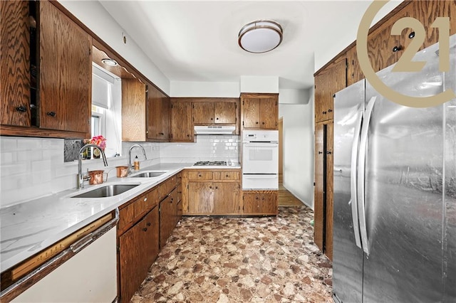 kitchen featuring white appliances, sink, and backsplash