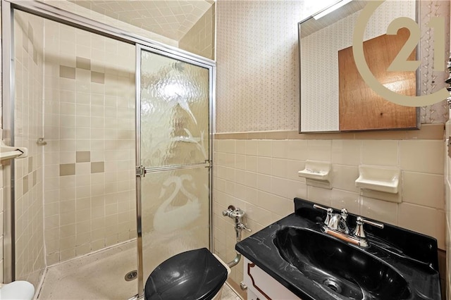 bathroom featuring vanity, toilet, a shower with shower door, and tile walls