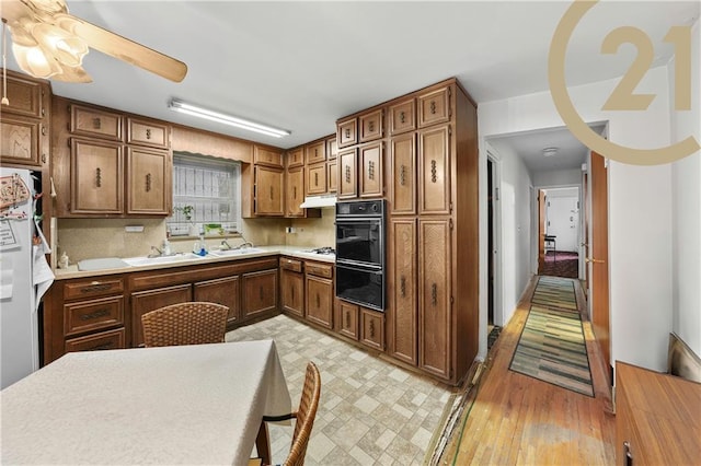 1736 E 7th St, Brooklyn, NY 11223 - kitchen with light countertops, ceiling fan, brown cabinets, under cabinet range hood, and refrigerator