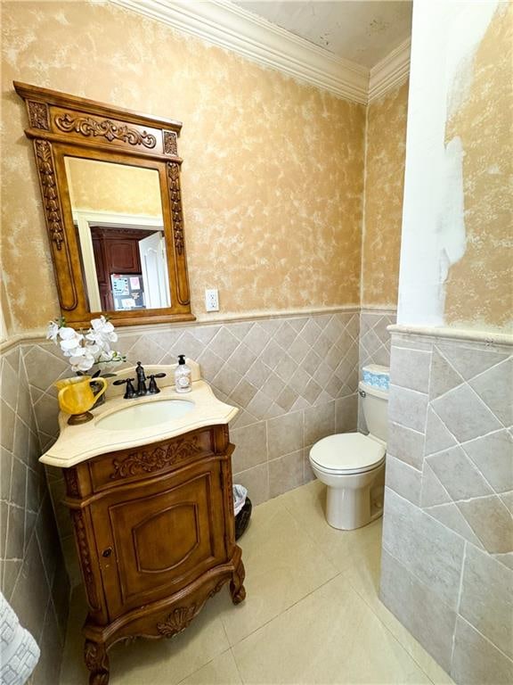 bathroom featuring tile patterned floors, toilet, crown molding, tile walls, and vanity