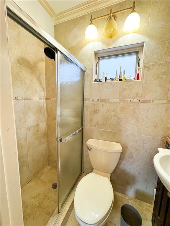 bathroom with ornamental molding, toilet, a shower with shower door, and tile walls