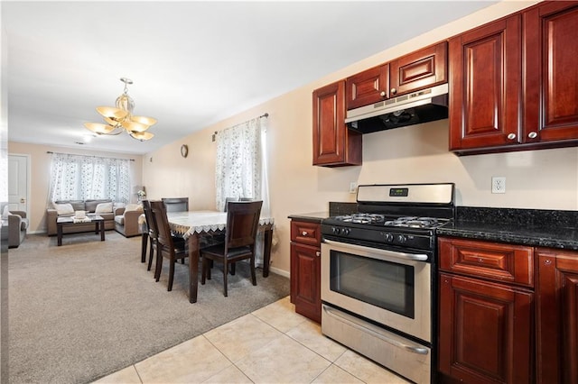 kitchen featuring an inviting chandelier, stainless steel range with gas cooktop, pendant lighting, light colored carpet, and dark stone counters