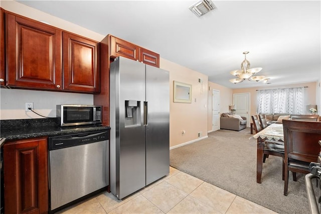 kitchen featuring decorative light fixtures, a chandelier, dark stone countertops, appliances with stainless steel finishes, and light colored carpet