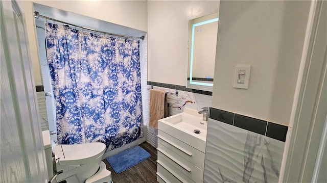 bathroom with hardwood / wood-style flooring, tile walls, vanity, curtained shower, and toilet