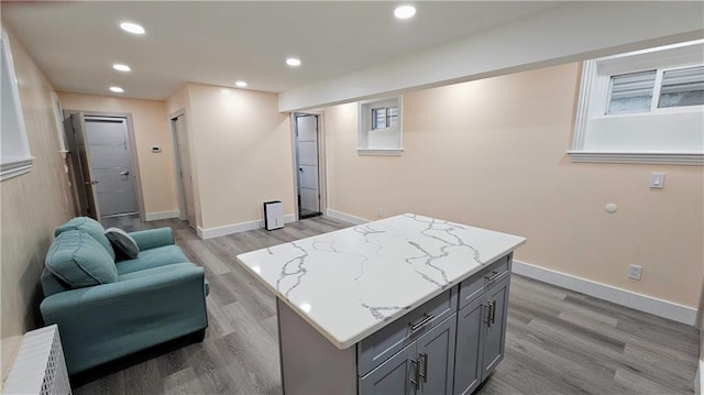 kitchen featuring gray cabinets, light stone countertops, light hardwood / wood-style floors, and a kitchen island