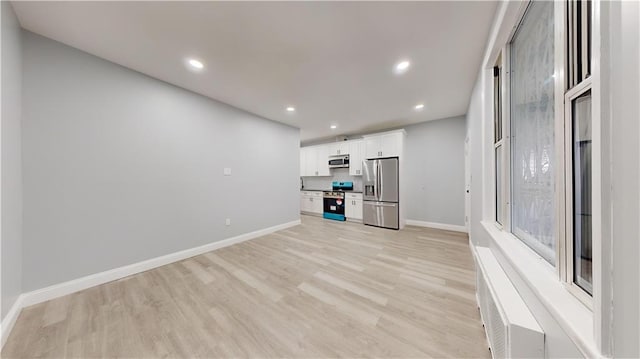 unfurnished living room featuring recessed lighting, light wood-style flooring, and baseboards