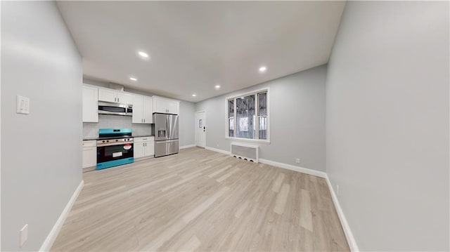 kitchen featuring light wood-style flooring, tasteful backsplash, white cabinetry, stainless steel appliances, and baseboards