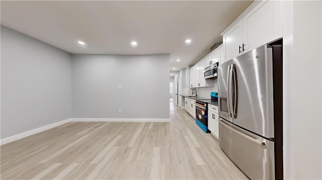 kitchen featuring light wood finished floors, backsplash, baseboards, appliances with stainless steel finishes, and white cabinets