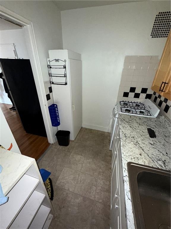 kitchen with tasteful backsplash, sink, and light stone countertops