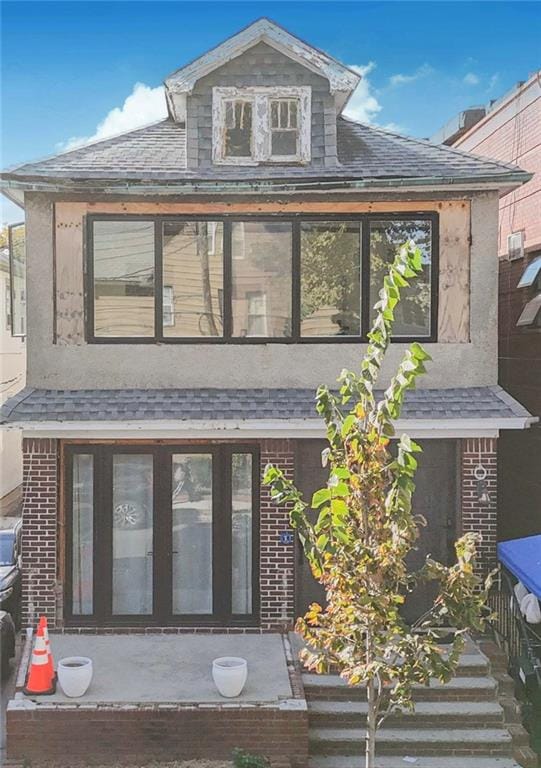 exterior space featuring roof with shingles and brick siding