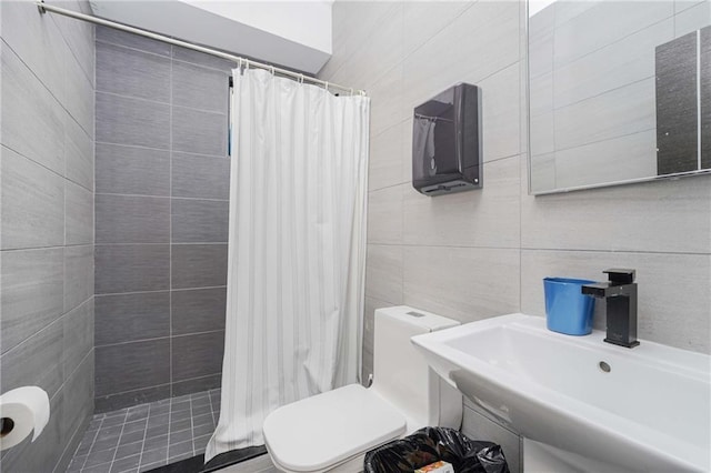 full bathroom featuring a shower stall, a sink, tile walls, and toilet