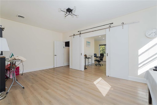 interior space with a barn door, light wood-type flooring, and baseboards