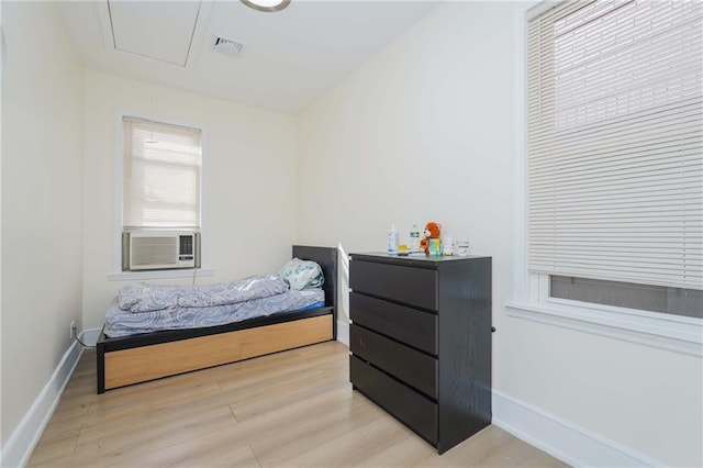 bedroom featuring visible vents, light wood-style flooring, attic access, cooling unit, and baseboards