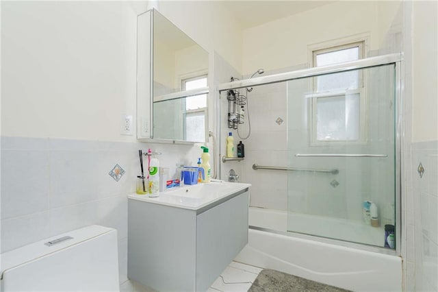 bathroom featuring enclosed tub / shower combo, tile patterned flooring, toilet, vanity, and tile walls