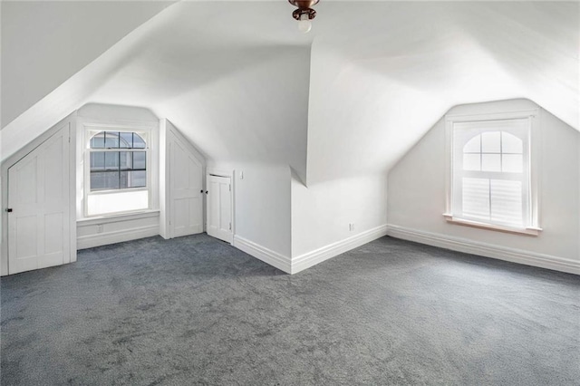 additional living space featuring lofted ceiling and dark carpet