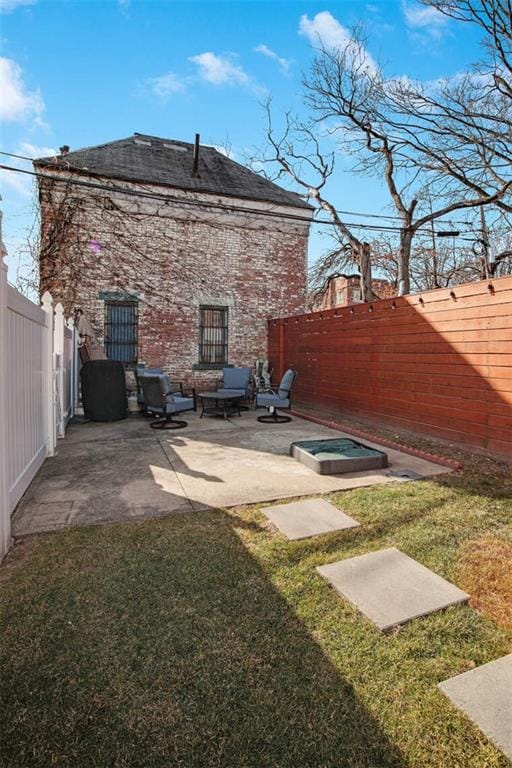 rear view of house featuring a hot tub, a patio area, and a lawn