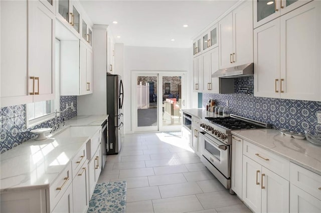 kitchen with stainless steel appliances, white cabinets, and light stone counters