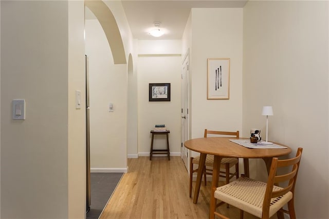 hallway featuring baseboards, arched walkways, and wood finished floors