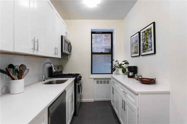 kitchen with appliances with stainless steel finishes, radiator, light countertops, and white cabinets