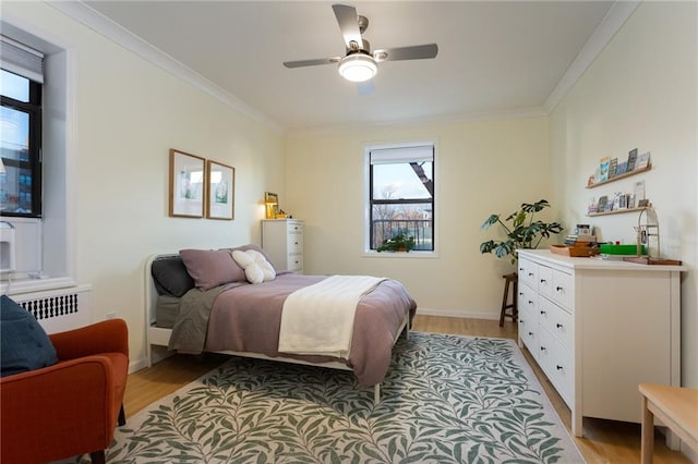 bedroom featuring light wood-type flooring, baseboards, crown molding, and radiator heating unit