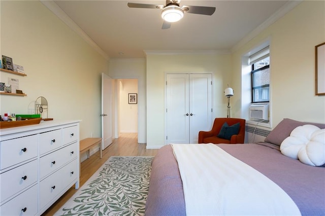 bedroom featuring a closet, light wood-style flooring, ornamental molding, a ceiling fan, and baseboards