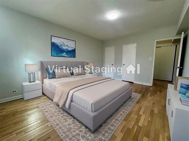 bedroom featuring wood-type flooring, baseboards, and two closets