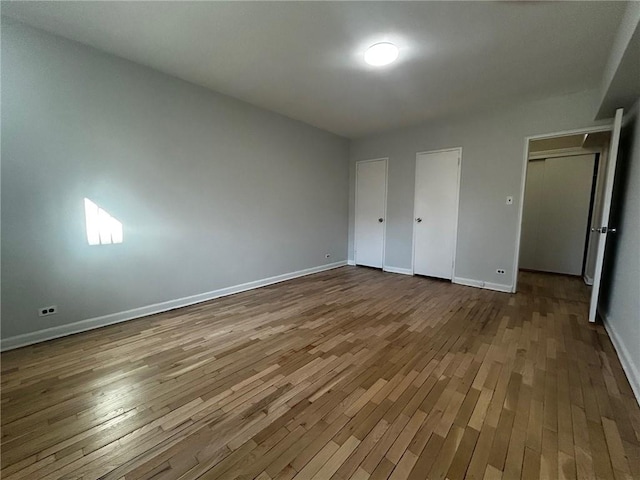 unfurnished bedroom with hardwood / wood-style flooring and baseboards