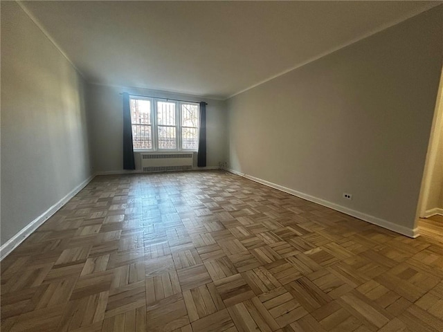 unfurnished room with baseboards, radiator heating unit, and crown molding