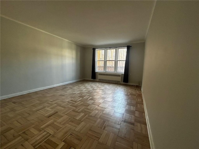 spare room featuring ornamental molding, radiator, and baseboards