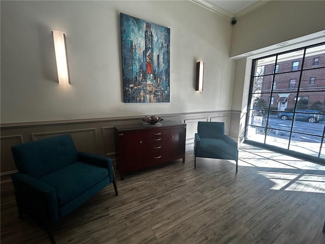 sitting room featuring ornamental molding, wainscoting, a decorative wall, and wood finished floors