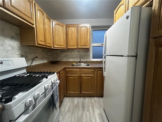 kitchen with white appliances, tasteful backsplash, dark countertops, light wood-type flooring, and a sink