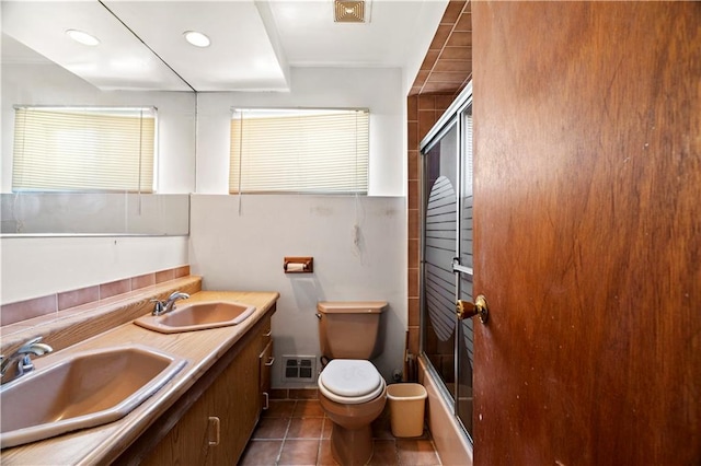 full bathroom featuring a sink, toilet, combined bath / shower with glass door, and tile patterned flooring