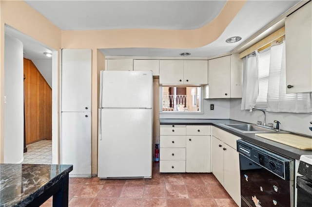 kitchen featuring freestanding refrigerator, a sink, black dishwasher, dark countertops, and range