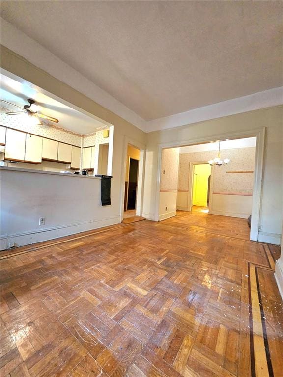 unfurnished living room featuring ceiling fan with notable chandelier