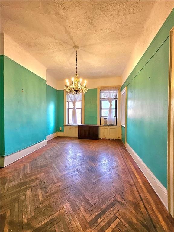 spare room featuring an inviting chandelier, dark parquet floors, and a textured ceiling